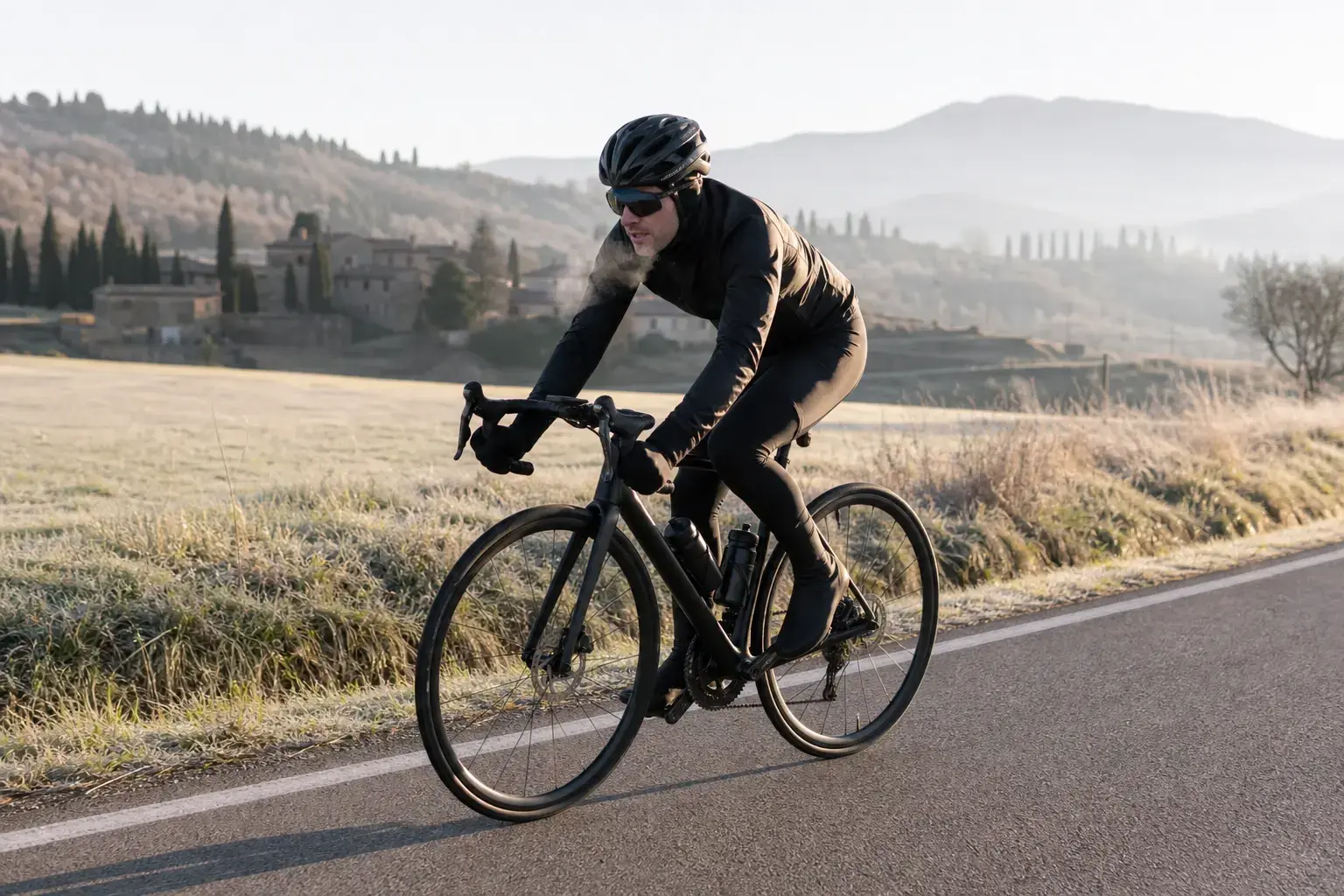 Ciclista durante un allenamento in bici con il freddo su una strada asciutta