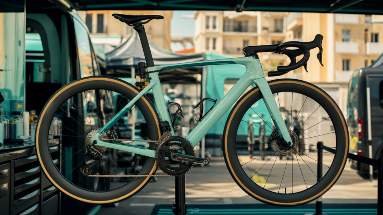 Illustrazione editoriale di una bici da corsa celeste ispirata al paddock del Tour de France 2026
