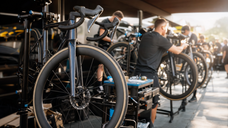 Illustrazione editoriale di un paddock tecnico al Tour de France con bici da corsa su cavalletti e meccanici al lavoro