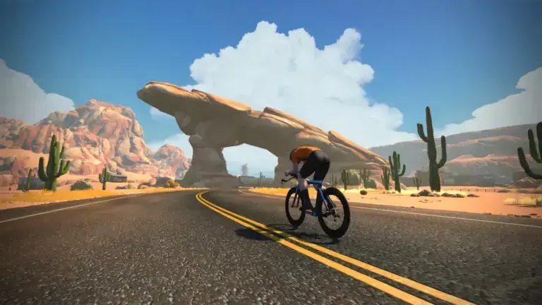 Schermata ufficiale Zwift: Fuego Flats e arco roccioso sul percorso Sand and Sequoias